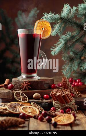 Bevanda calda di Natale con spezie, agrumi secchi e mirtilli rossi su un vecchio tavolo di legno. Foto Stock