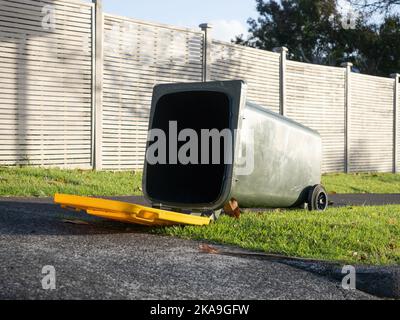 Vista dei cassonetti delle ruote dei rifiuti rovesciati dal forte vento che si posa a terra Foto Stock