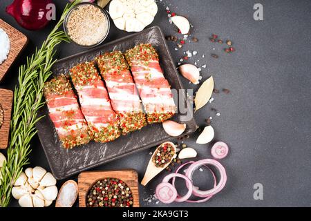 Tradizionale cibo balcanico cevapcici o rumeno mitigei pronti per grigliare o barbecue. Involtini di carne macinata cruda avvolti con pancetta e condimenti in contenitore Foto Stock