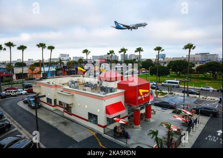 L'aereo Alaska Airlines sorvola il ristorante in-N-out Burger mentre atterra all'aeroporto internazionale di Los Angeles LAX Foto Stock