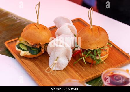 Hamburger freschi e deliziosi alla griglia su un tavolo di legno. Street food festival. Foto Stock