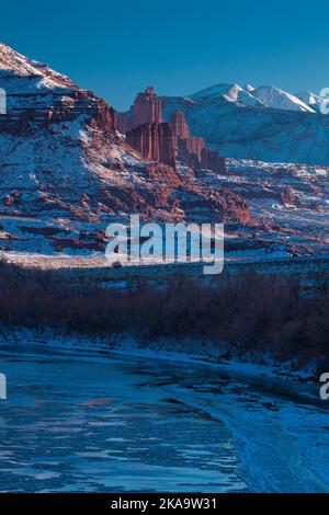 Fisher Towers sul ghiacciato fiume Colorado al tramonto in inverno con le montagne la SAL dietro. Vicino a Moab, Utah. Foto Stock