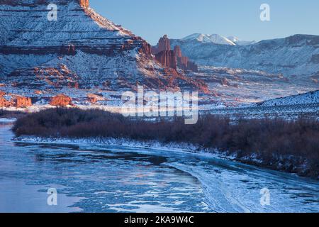 Fisher Towers sul ghiacciato fiume Colorado al tramonto in inverno con le montagne la SAL dietro. Vicino a Moab, Utah. Foto Stock