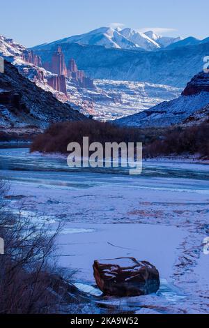 Fisher Towers sul ghiacciato fiume Colorado al tramonto in inverno con le montagne la SAL dietro. Vicino a Moab, Utah. Foto Stock