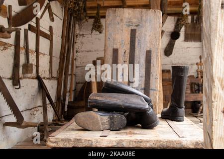 Vecchi stivali si trovano su un tavolo di legno in un villaggio in fienili in Ucraina, scarpe da vecchio uomo Foto Stock