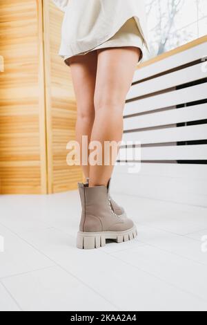 Scarpe da donna in pelle. Gambe femminili sottili in stivali in pelle beige. Stivali da donna alla moda. Foto Stock