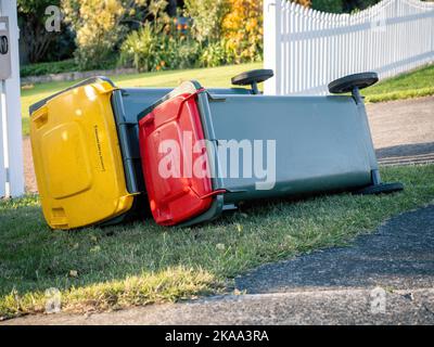 Vista dei cassonetti delle ruote dei rifiuti rovesciati dal forte vento che si posa a terra Foto Stock