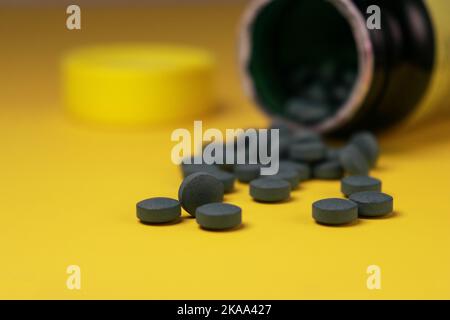 primo piano di ferro verde pillole vitamine su sfondo giallo Foto Stock