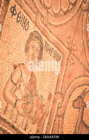 Petra, Giordania - 7th ottobre 2022: Gli esseri umani affrontano l'arte del mosaico sul pavimento nella chiesa bizantina nel sito storico di Petra Foto Stock