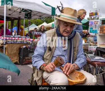 Poeta e autore Ian Bailey intagliando una ciotola di legno con uno scalpello. Foto Stock