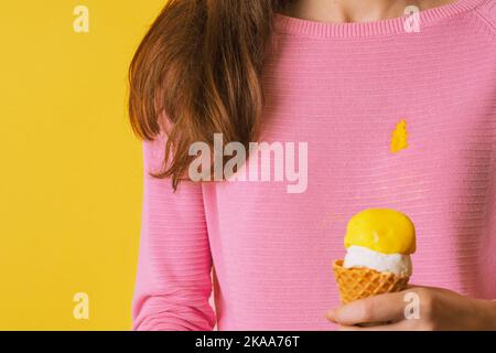 La ragazza che indossa blusa macchiata che tiene gelato. Versare il gelato sui vestiti Foto Stock