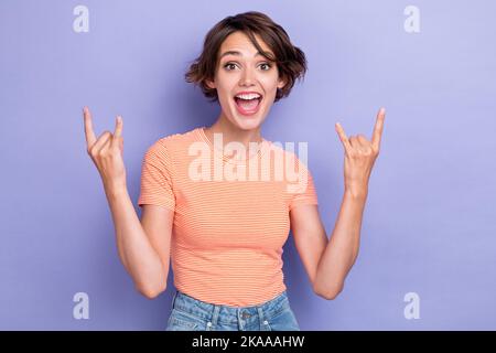 Foto di giovane carino bella splendida donna pazzo eccitato umore positivo mostra segno rocker musica amante spensierato isolato su colore viola pastello Foto Stock