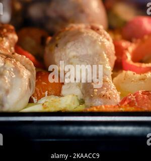 Cucinare il pollo con le verdure nel forno. Cosce e cosce di pollo con marinata, patate, pomodori e paprika Foto Stock