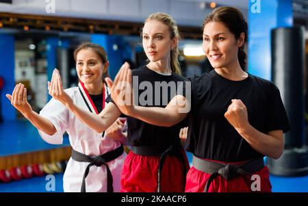 Tre giovani donne sorridenti che praticano il karate Foto Stock