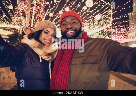 Foto di allegro marito divertente moglie indossare abiti stagione invernale tacking selfie xmas mercato urbano città strada Foto Stock
