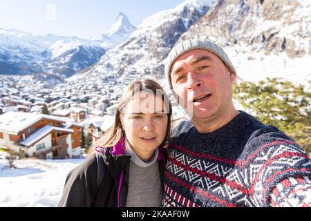Coppia felice che prende selfie sullo sfondo delle montagne mentre viaggia insieme Foto Stock