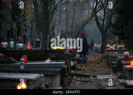 Varsavia, Polonia. 01st Nov 2022. La gente mette le candele sulle tombe dei loro cari durante la nebbia il giorno di tutti i santi al cimitero di Pow?zki. Giorno di tutti i Santi/giorno di tutte le ANIME (o Dzie? Zaduszny in polacco) è una festa pubblica e un'opportunità per ricordare i morti. In questo giorno la gente porta fiori e candele ai cimiteri. Nel buio tutto il cimitero è pieno di luci. Il cimitero di Pow?zki (o Old Pow?zki) è una necropoli storica di Varsavia. È il cimitero più famoso della città e uno dei più antichi. Credit: SOPA Images Limited/Alamy Live News Foto Stock