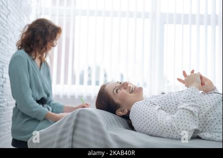 Una donna di mezza età si trova su un divano e parla con uno psicologo. Foto Stock