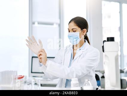 Sperimentiamo. Un giovane scienziato indossa guanti chirurgici mentre lavora in laboratorio. Foto Stock