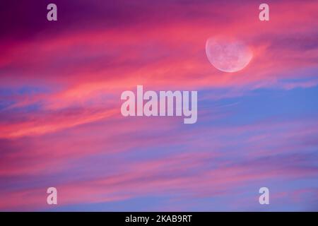 The Moon is Rising Among A colorful Cloud Ffilled Sunset Sky High Resolution Foto Stock