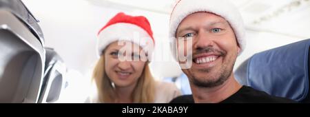 Uomo e donna in rosso babbo natale cappelli volare in aereo Foto Stock