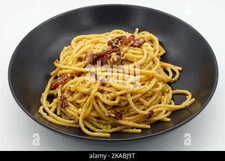 Spaghetti alla Carbonara Pasta in un piatto nero isolato su bianco. Foto Stock