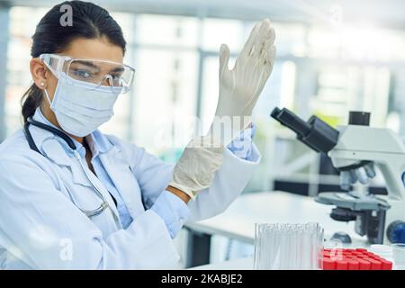 Lascia ottenere sperimentando. Ritratto di un giovane scienziato che indossa guanti protettivi mentre lavora in laboratorio. Foto Stock