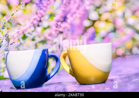 Tazze da tè da caffè gialle e blu su sfondo floreale rosa Foto Stock