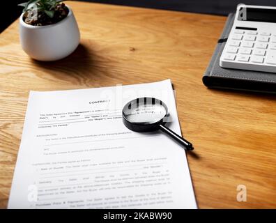 Contratto di carta su scrivania in legno con lente d'ingrandimento. Foto Stock