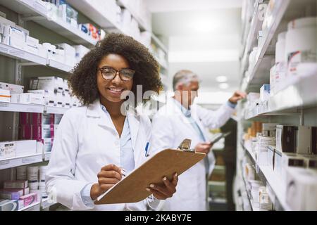 Siamo sempre in movimento. Ritratto di una giovane ragazza giovane e allegra farmacista in possesso di una clipboard e fare scorta mentre si guarda la macchina fotografica. Foto Stock