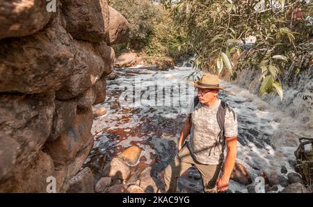 Uomo maturo backpacker escursioni, in viaggio tra rocce e acqua in estate. Escursionista esplorando la natura. Foto Stock