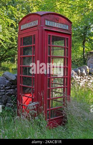 Scatola telefonica rossa in piedi in High Grass di fronte a un muro di pietra naturale a secco catasta, Giura, Ebridi, Ebridi interne, Isole interne, Scozia, Regno Unito Foto Stock