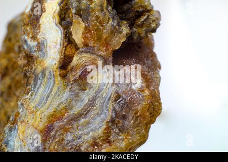 Chunk di agata cruda brillante, chalcedonia di agata bruna, gialla e bianca con agata drusa e piccoli punti di pietra cristallina macro in primo piano isolati Foto Stock