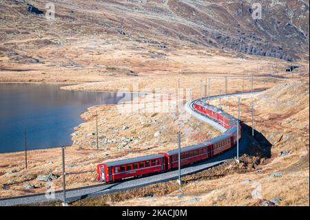 Vista panoramica di un treno rosso nelle Alpi svizzere della compagnia ferroviaria Rhätische Bahn. Foto Stock