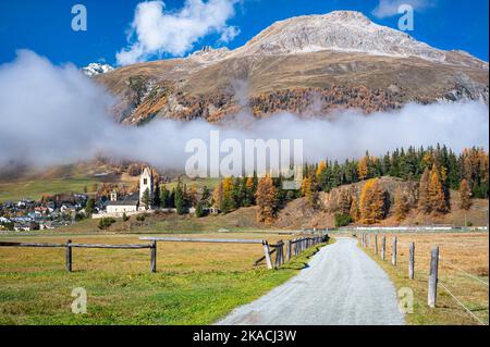 Vista panoramica di una strada che conduce alla Chiesa Riformata di San Gian, nella città di Celerina, nella valle dell'Engadina, nel Cantone di Graubünden, Svizzera. Foto Stock