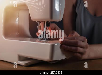 Mani inserire il filo attraverso il foro dell'ago nella macchina da cucire, dettagli. Foto Stock