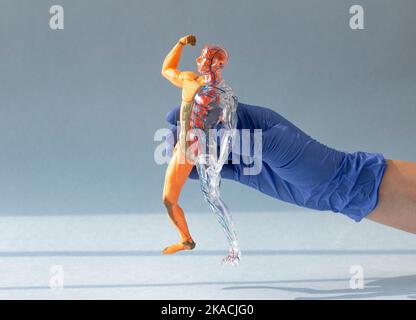 Mano del medico nel guanto che si inforra al corpo umano modello 3D senza pelle con sistemi circolatori e muscolari su sfondo blu. Concetto di anatomia. Foto Stock