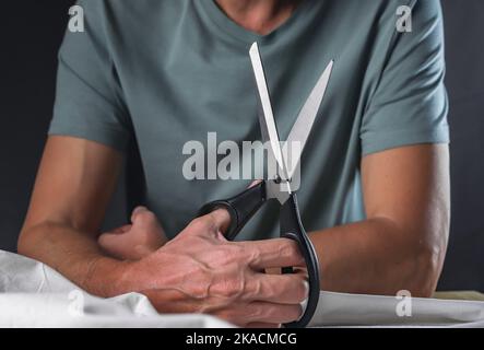 Mani maschili con forbici professionali per cucire su misura. Foto Stock