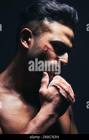 Lesioni, sangue e uomo con un bendaggio da combattimento o formazione per MMA o kickboxing in uno studio buio. Violenza, ferite e pugile dal Messico dopo Foto Stock