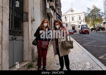 DONNE, COVID, MASCHERE FACCIALI, LISBONA: Una scena di strada come il blocco termina nella città vecchia di Lisbona, Portogallo, marzo 2022. Foto di Rob Watkins Foto Stock