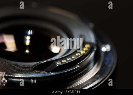 Il lato opposto di una lente moderna con contatti sulla baionetta. Fotografia macro su sfondo scuro con profondità di campo ridotta Foto Stock