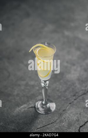 cocktail francese di champagne 75 con tocco limone guarnire in flauto vetro contro cemento rustico Foto Stock