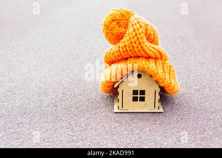 Giocattolo casa di legno con chunky cappello caldo sulla parte superiore isolato sul grigio. Concetto di sviluppo domestico efficiente dal punto di vista energetico. Foto Stock