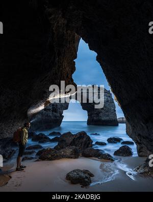 Uomo in piedi nella grotta costiera Foto Stock