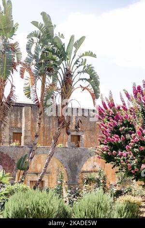 Uno scatto verticale dell'antico monastero di Agia Triada a Creta, in Grecia, circondato da lussureggianti palme Foto Stock