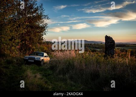 Sady, Polonia - 12 ottobre 2022: Una classica auto dorata Mercedes Benz 190 fuori strada in campagna. Paesaggio autunnale al tramonto con una collina di Great Owl. Foto Stock