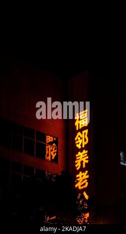 Uno scatto verticale di un segno al neon con logogrammi cinesi Foto Stock