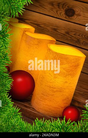 Quattro candele LED d'epoca d'oro in vera cera con rami di abete e palle rosse di Natale su sfondo di legno Foto Stock