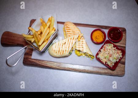 Panini affettati in due porzioni con patatine fritte e un piccolo recipiente per insalata Foto Stock