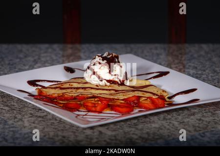 Un primo piano di gelato con frittelle e fragole sul piatto Foto Stock